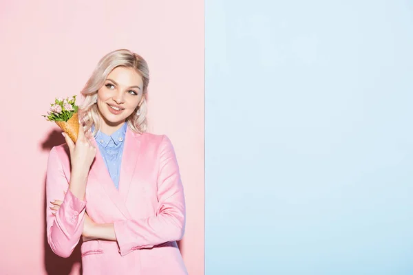 Mujer soñadora sosteniendo ramo sobre fondo rosa y azul - foto de stock