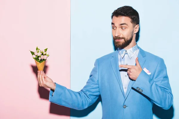 Uomo sorridente che punta con bouquet dito su sfondo rosa e blu — Foto stock