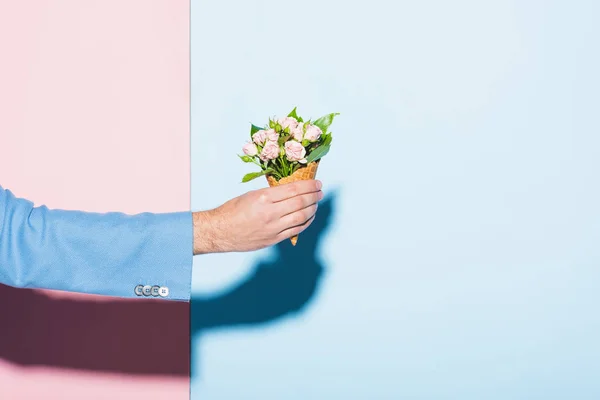 Vista cortada do homem segurando buquê no fundo rosa e azul — Fotografia de Stock