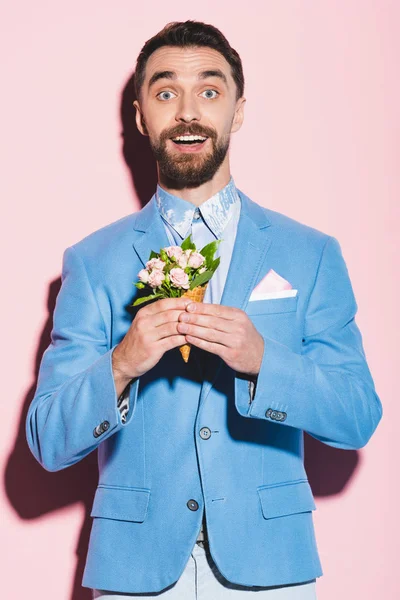 Shocked man holding bouquet on pink and blue background — Stock Photo