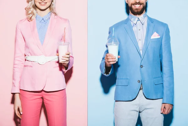 Cropped view of smiling woman and man holding cocktails on pink and blue background — Stock Photo