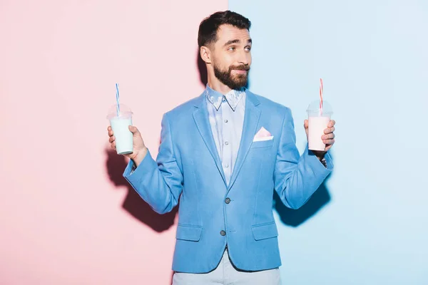 Homme souriant tenant des cocktails sur fond rose et bleu — Photo de stock