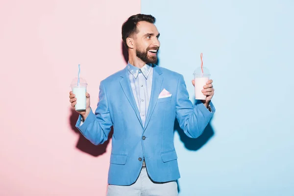 Uomo sorridente che tiene cocktail su sfondo rosa e blu — Foto stock