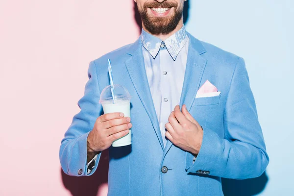 Vue recadrée d'un homme souriant tenant un cocktail sur fond rose et bleu — Photo de stock