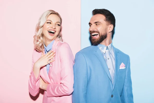 Attractive woman and handsome man smiling on pink and blue background — Stock Photo