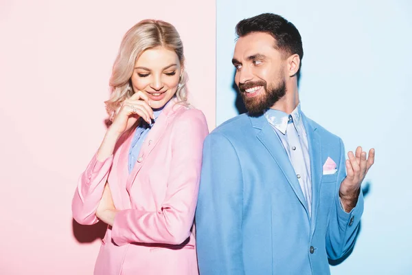 Attractive woman and handsome man smiling on pink and blue background — Stock Photo