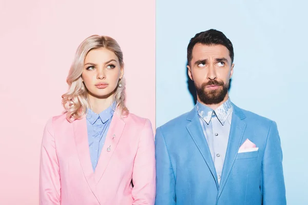 Dreamy woman and handsome looking away man on pink and blue background — Stock Photo