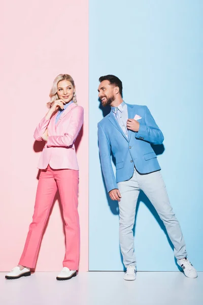 Femme rêveuse et bel homme la regardant sur fond rose et bleu — Photo de stock