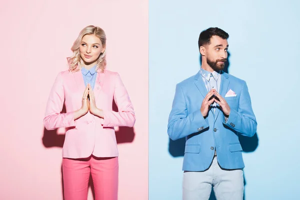 Donna e uomo sognanti con le mani in preghiera su sfondo rosa e blu — Foto stock