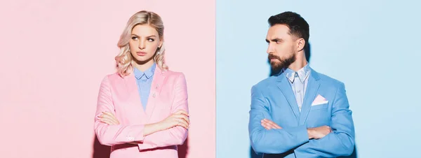 Panoramic shot of sad woman and handsome man with crossed arms on pink and blue background — Stock Photo