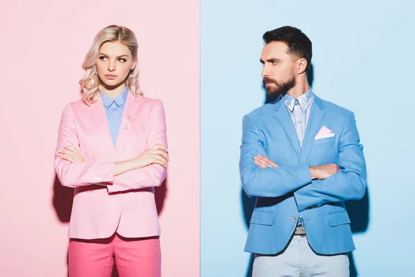 Sad woman and handsome man with crossed arms on pink and blue background — Stock Photo