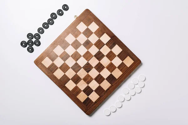 Top view of wooden chessboard and checkers on white background — Stock Photo