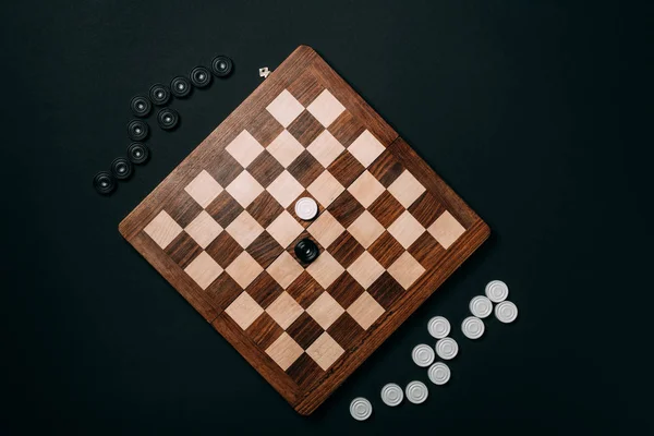 Top view of checkers on wooden chessboard isolated on black — Stock Photo