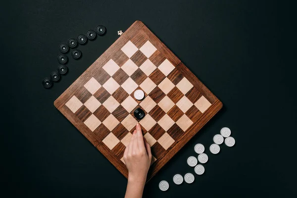 Cropped view of woman hand on chessboard with checkers isolated on black — Stock Photo