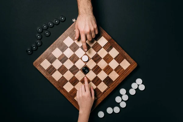 Top view of man and woman playing checkers isolated on black — Stock Photo