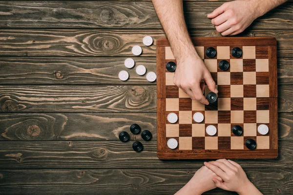Top view of couple playing checkers on wooden background — Stock Photo