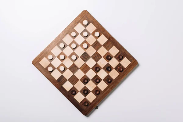 Top view of checkers on wooden chessboard on white background — Stock Photo