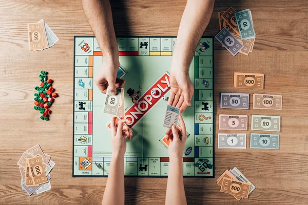 KYIV, UCRAINA - 15 NOVEMBRE 2019: Vista ritagliata di uomo e donna che giocano a gioco monopolistico a tavola — Foto stock