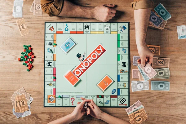 KYIV, UKRAINE - NOVEMBER 15, 2019: Top view of woman with dices and man holding toy currency while playing in monopoly — Stock Photo