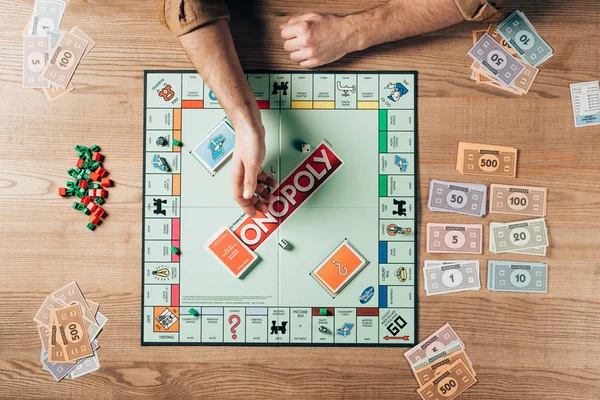 KYIV, UKRAINE - NOVEMBER 15, 2019: Top view of man throwing dices on monopoly game at table — Stock Photo