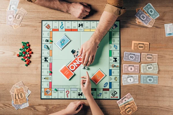 KYIV, UKRAINE - NOVEMBER 15, 2019: Cropped view of man and woman playing monopoly with toy currency on table — Stock Photo