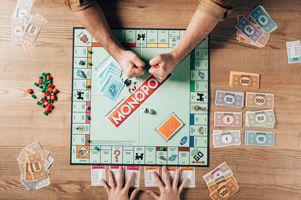 KYIV, UKRAINE - NOVEMBER 15, 2019: Cropped view of man celebrating triumph while playing with woman in monopoly — Stock Photo