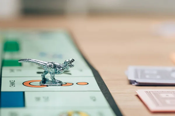 QUIIV, UCRÂNIA - NOVEMBRO 15, 2019: Foco seletivo de jogar figura no jogo de monopólio com moeda de brinquedo na mesa — Fotografia de Stock