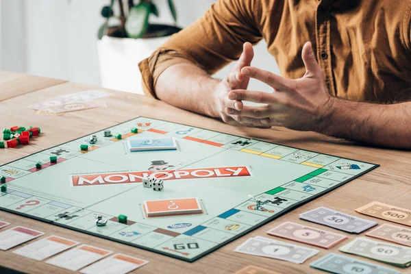 Kyiv, Ukraine - 15. November 2019: Ausgeschnittene Ansicht eines Mannes, der mit Monopoly-Spiel am Tisch sitzt — Stockfoto