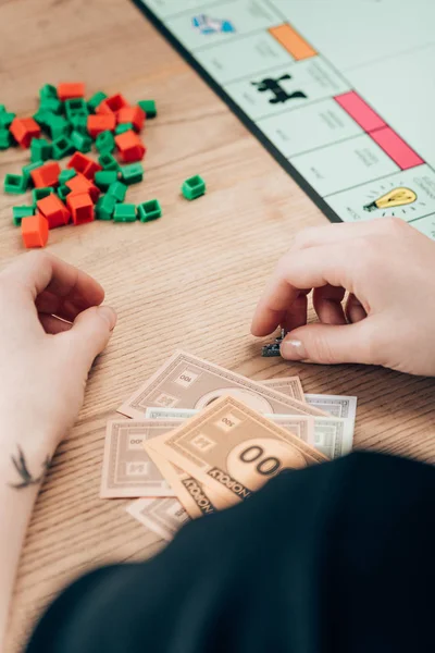 KYIV, UKRAINE - NOVEMBER 15, 2019: Cropped view of woman playing monopoly game at wooden table — Stock Photo