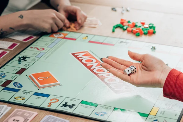 KYIV, UKRAINE - NOVEMBER 15, 2019: Cropped view of woman playing monopoly game at table — Stock Photo