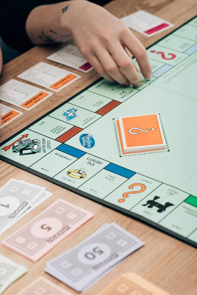 KYIV, UKRAINE - NOVEMBER 15, 2019: Cropped view of woman playing monopoly game at wooden table — Stock Photo