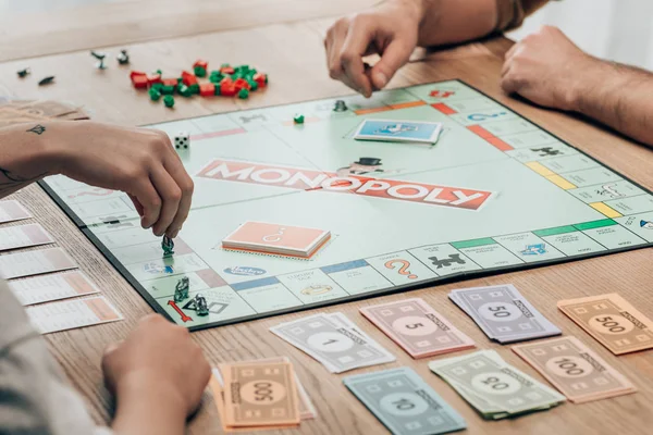 KYIV, UKRAINE - NOVEMBER 15, 2019: Cropped view of man and women playing monopoly game at table — Stock Photo