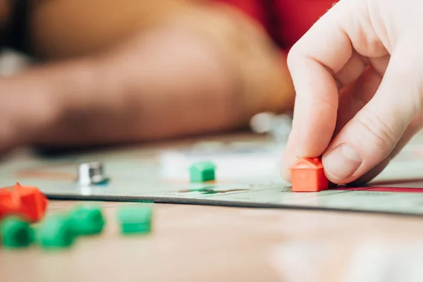 KYIV, UCRANIA - 15 DE NOVIEMBRE DE 2019: Vista recortada de la mujer sosteniendo la figura del juego monopolista en la mesa — Stock Photo