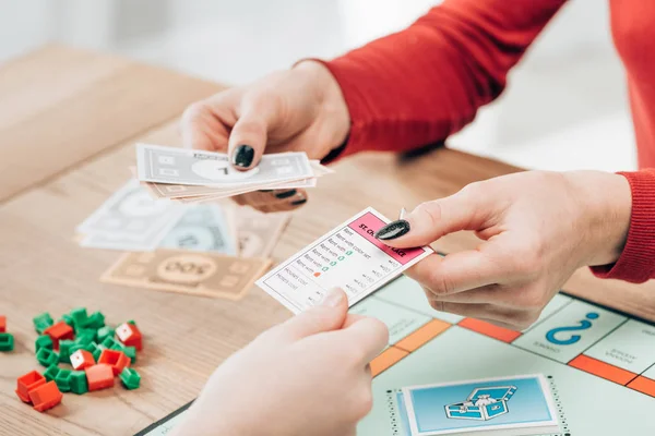 KYIV, UKRAINE - NOVEMBER 15, 2019: Cropped view of women playing monopoly game at table — Stock Photo