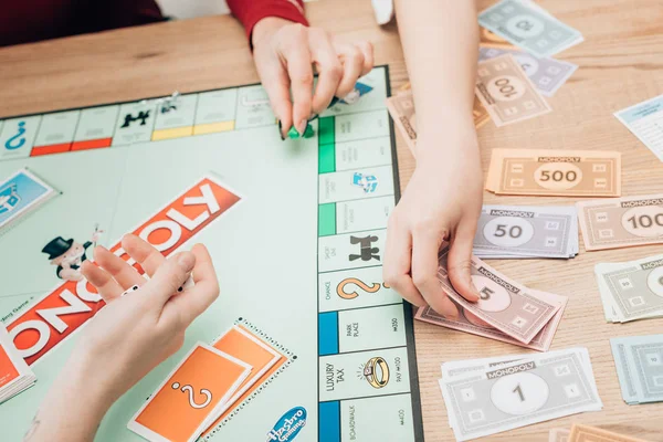 KYIV, UKRAINE - NOVEMBER 15, 2019: Cropped view of women playing monopoly game at table — Stock Photo