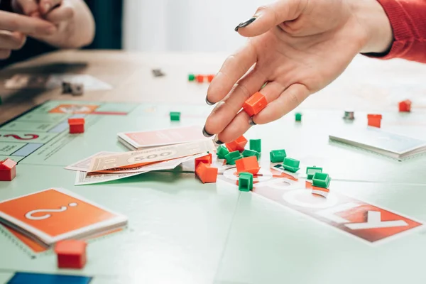 KYIV, UKRAINE - NOVEMBER 15, 2019: Cropped view of woman holding toy figure of monopoly game at table — Stock Photo