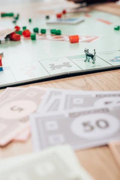 KYIV, UKRAINE - NOVEMBER 15, 2019: Selective focus of figures and toy currency of monopoly game on table — Stock Photo