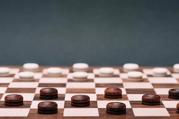 Selective focus of checkers on checkerboard isolated on grey — Stock Photo
