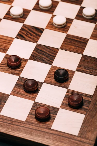 High angle view of checkers on wooden checkerboard — Stock Photo