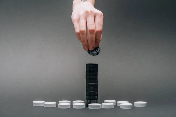 Cropped view of woman stacking checkers isolated on grey — Stock Photo