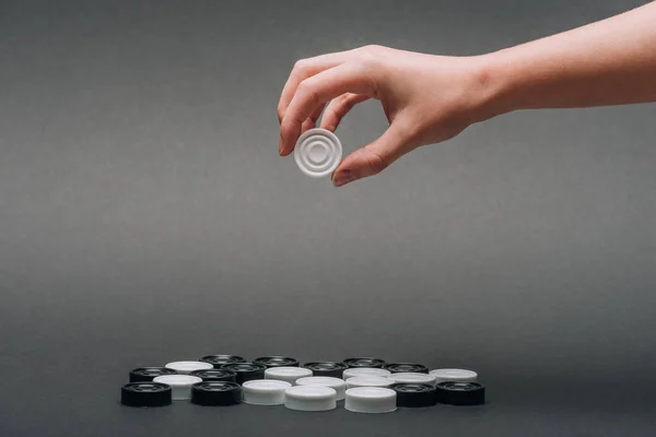 Cropped view of woman holding white checker isolated on grey — Stock Photo