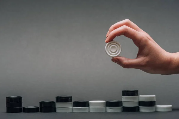 Cropped view of woman holding white checker with checkers isolated on grey — Stock Photo