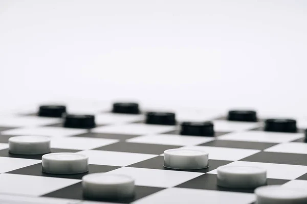 Selective focus of checkers on chessboard isolated on white — Stock Photo