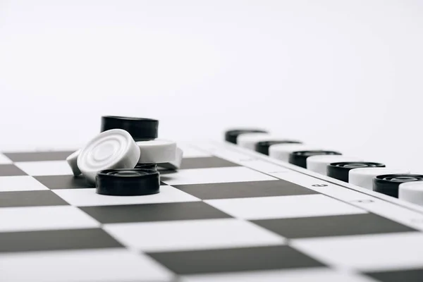 Enfoque selectivo de las damas en blanco y negro en el tablero de ajedrez aislado en blanco - foto de stock