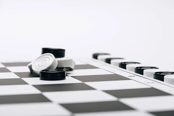 Mise au point sélective de damiers noirs et blancs sur damier isolé sur blanc — Photo de stock