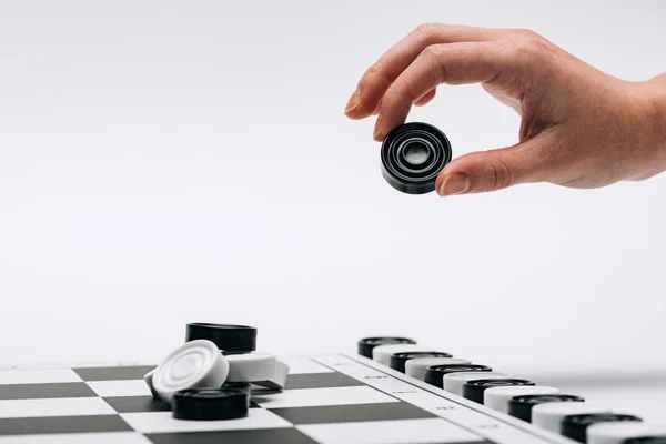Cropped view of woman holding black checker with checkerboard isolated on white — Stock Photo