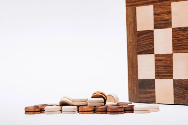 Damas de madera por tablero de ajedrez aisladas en blanco - foto de stock