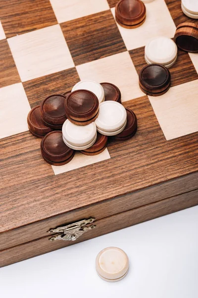 High angle view of wooden checkers on checkerboard isolated on white — Stock Photo