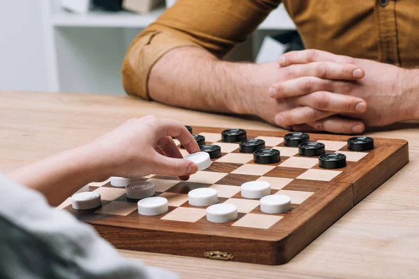 Cropped view of man and woman playing checkers at table — Stock Photo