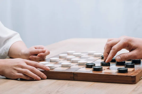 Vista recortada de la mujer y el hombre jugando damas en la mesa - foto de stock